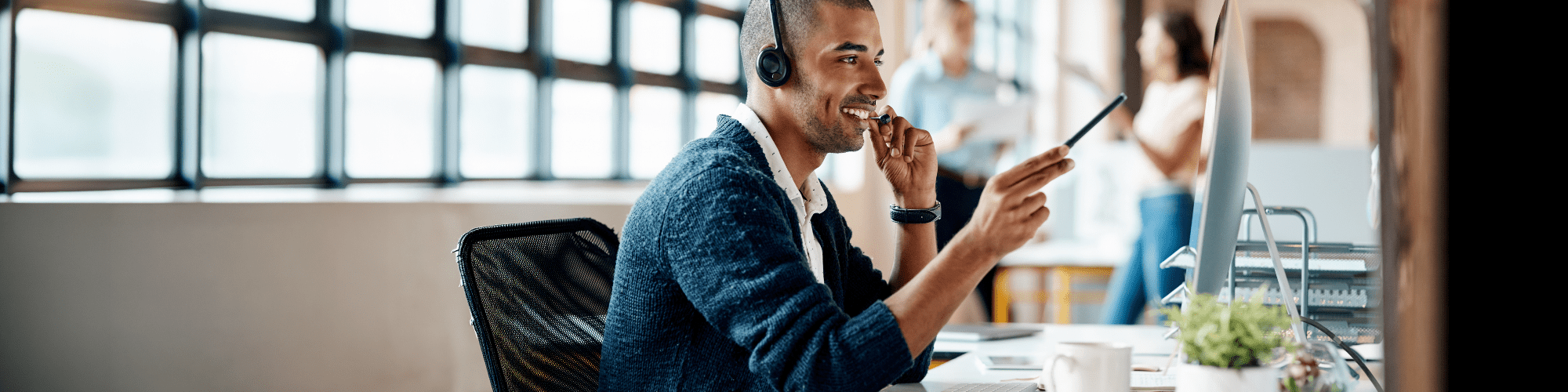 Freundlicher Kundenberater mit Headset in einem modernen Büro – persönlicher Service und direkte Erreichbarkeit.